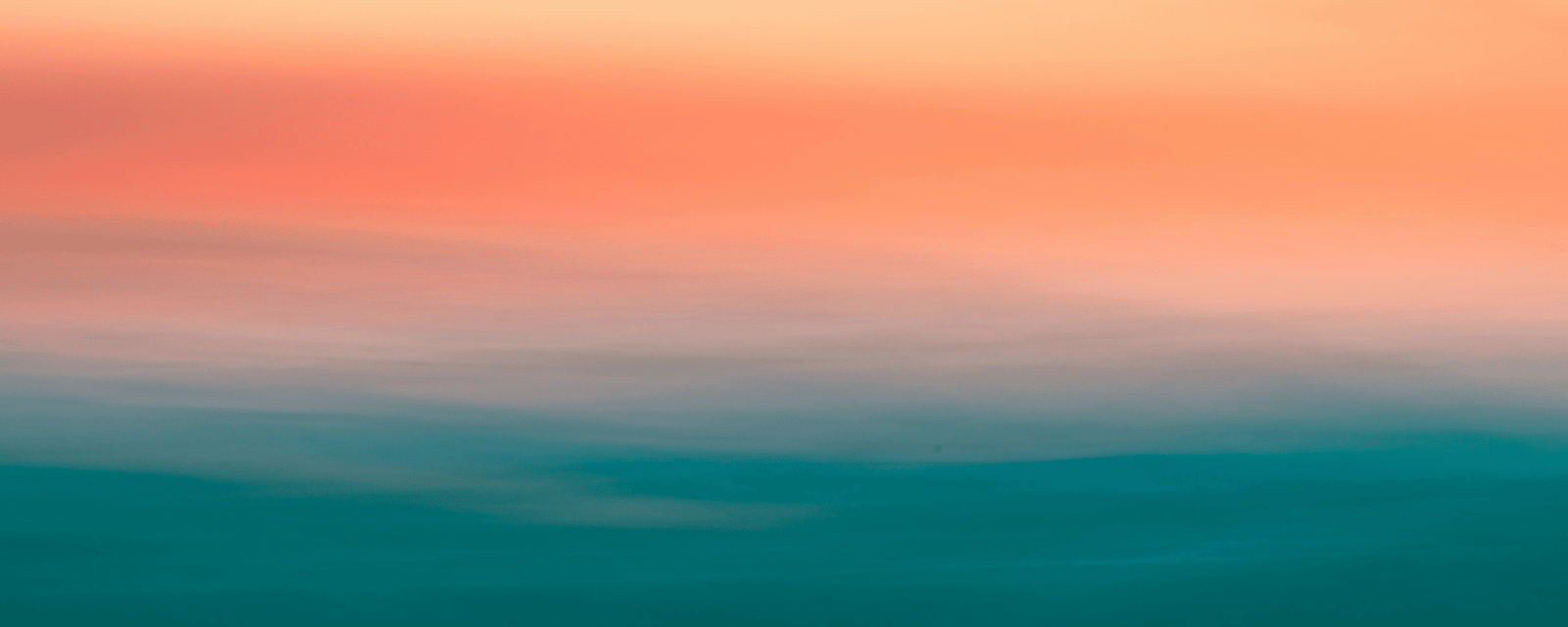 A hazy horizon where coral sky fades into a soft teal sea