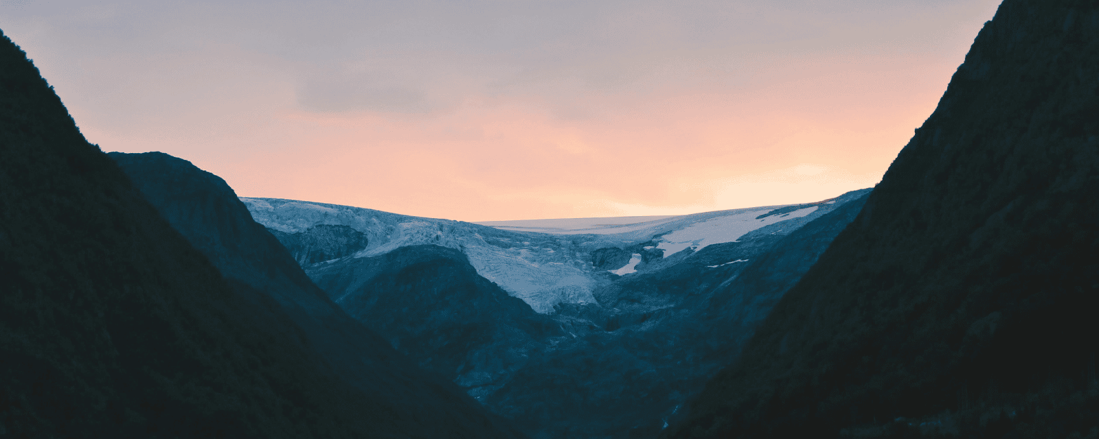 A quiet Norwegian mountain valley with snow and glacier at sunset